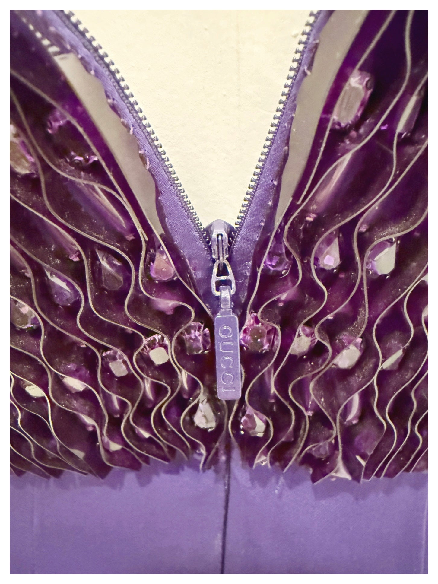 Close-up of Gucci-branded zipper surrounded by purple pleated satin and beaded embellishment on the back of the gown.