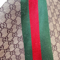 Detailed close-up of Gucci GG monogram pattern with signature green red web stripe