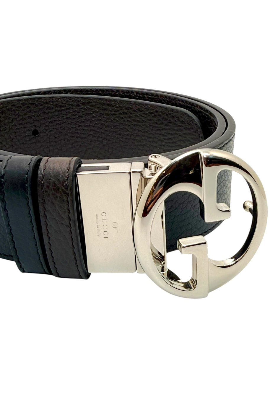 Close-up of Gucci silver-tone Interlocking G buckle on black grained leather belt, showcasing iconic GG logo hardware and luxury craftsmanship.