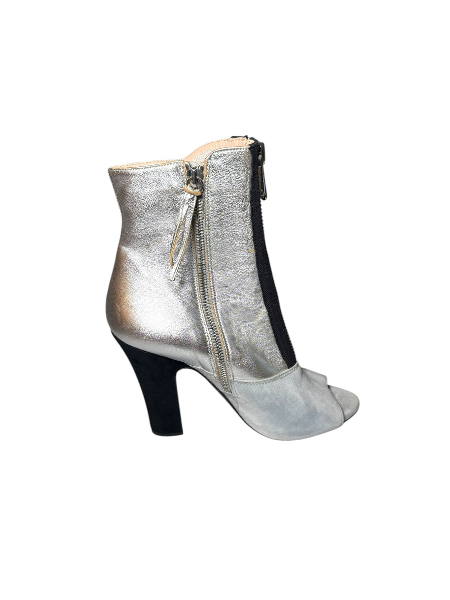 Silver Miu Miu high-heeled bootie left shoe facing right to show inner outside view of the shoe with a zipper on a white background