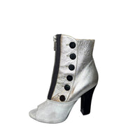 Silver Miu Miu left outside view of ankle bootie with black buttons on a white background