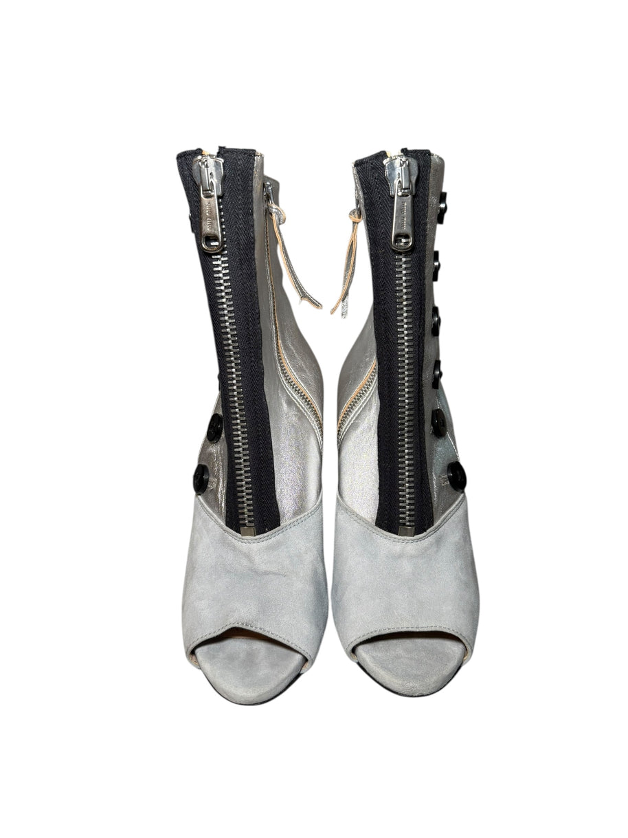 Pair of Miu Miu gray and silver peep-toe booties with zippers on a white background