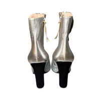 Silver Pair of Miu Miu high-heeled boots showing rear view of shoes on a white background