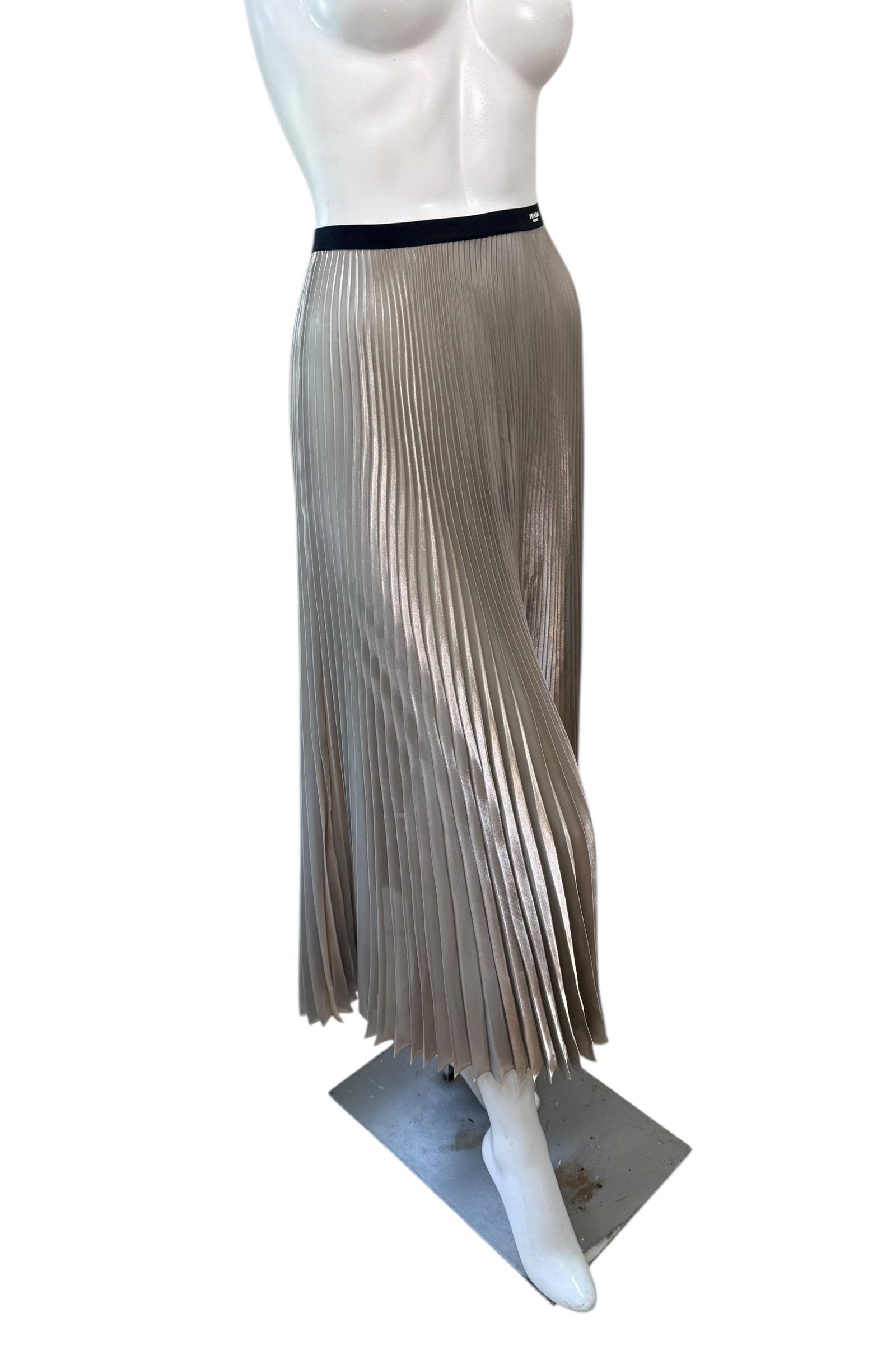 Side view of Prada metallic pleated midi skirt featuring flowing champagne silver plissé construction and high-waisted silhouette.