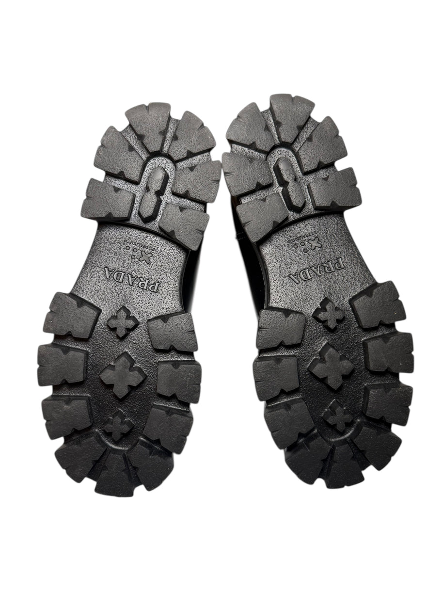 Black rubber sole of Prada monolith chelsea boots with Prada brand logo on a white background