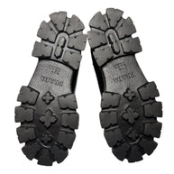 Black rubber sole of Prada monolith chelsea boots with Prada brand logo on a white background