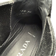 Close-up of a black Prada shoe with 'Made in Italy' Size '39' and 'Prada' brand label text on the inside sole and tongue.