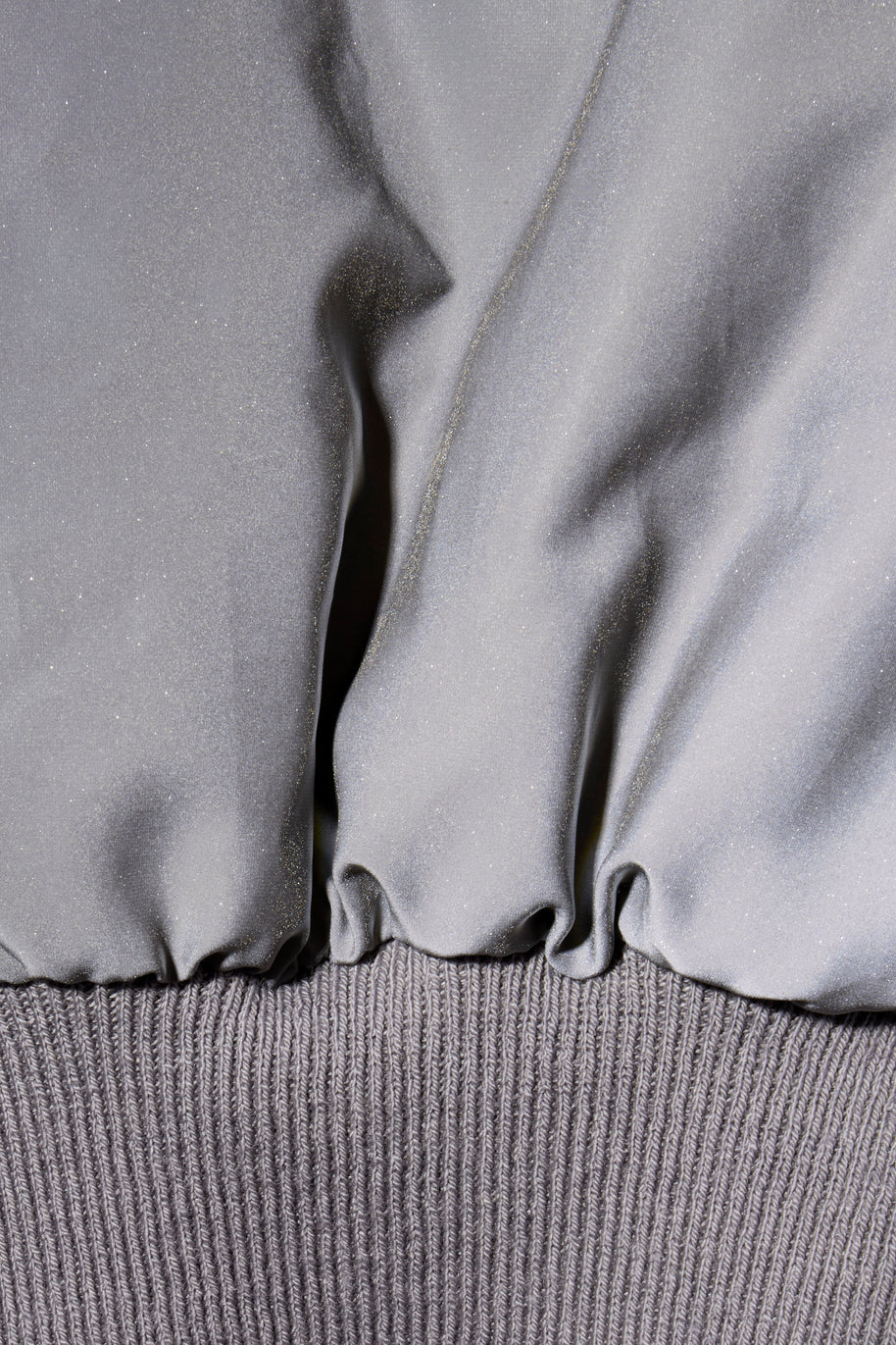 Rick Owens Bomber Jacket Close-up of a metallic gray fabric texture with ribbed waist band on FW22 Strobe jacket.
