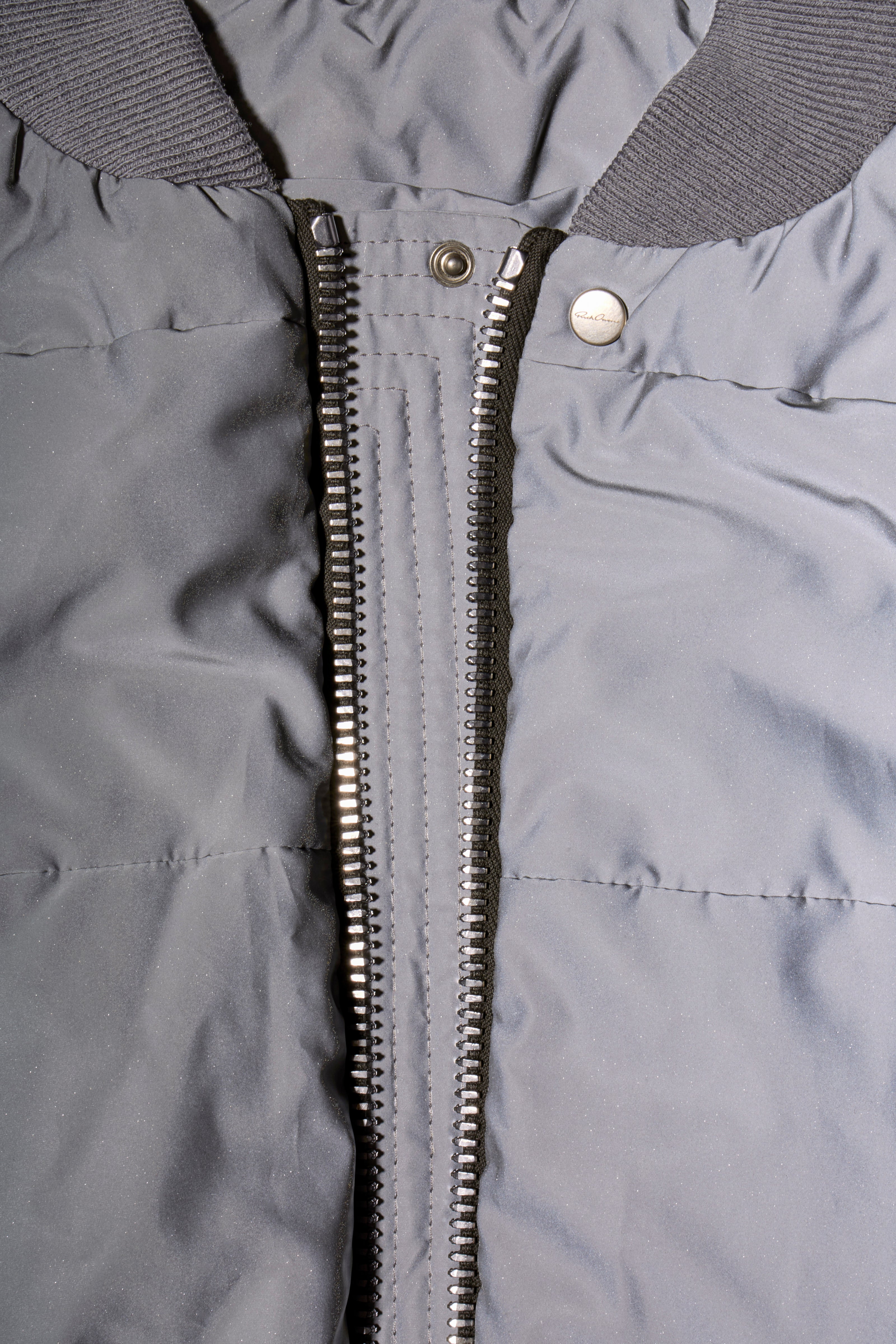 Close-up of Rick Owens Strobe collection gray bomber jacket with a zipper and Rick Owens label on snap button