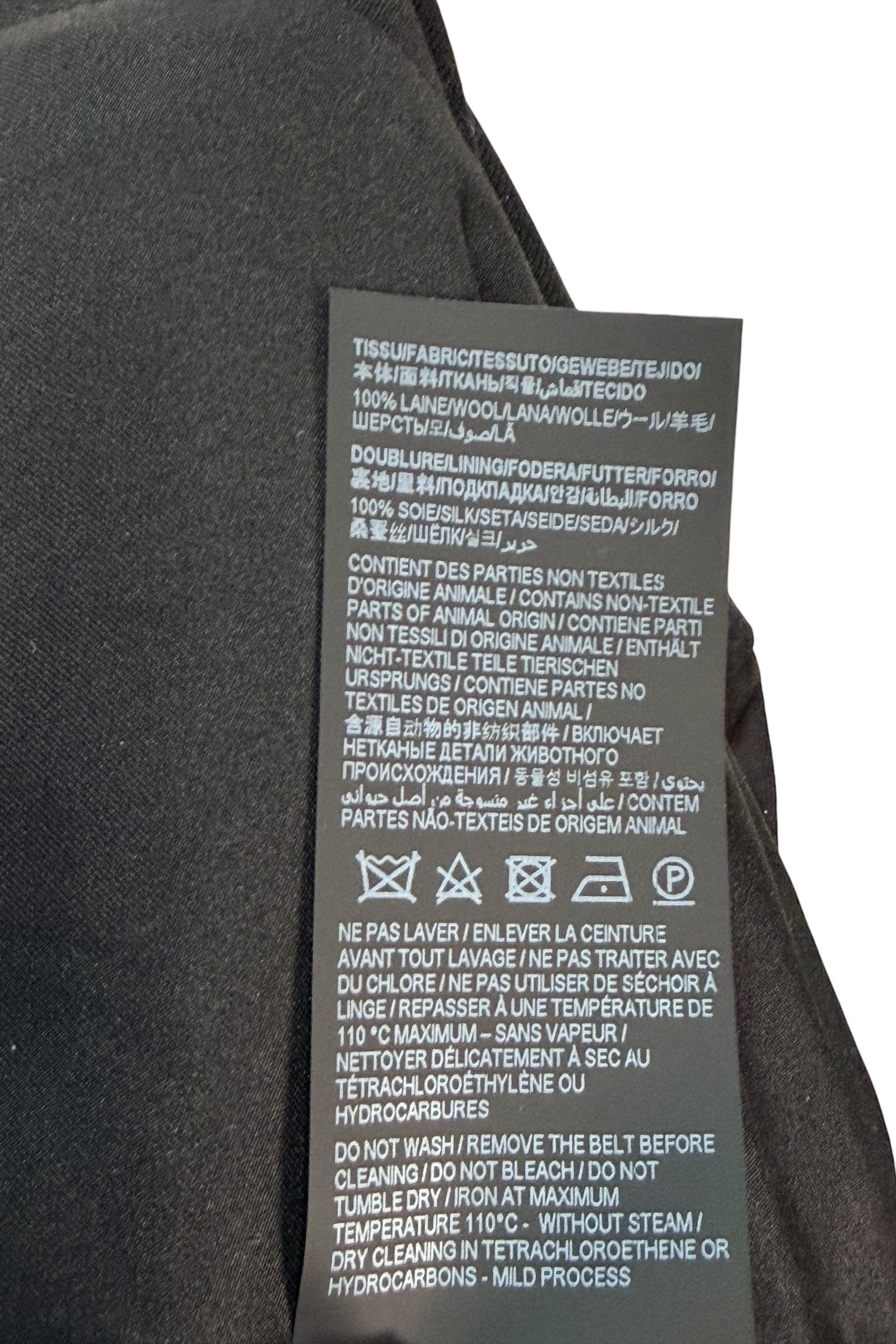 Fabric composition and care label of Saint Laurent Paris black wool jumpsuit with silk lining and cleaning instructions.