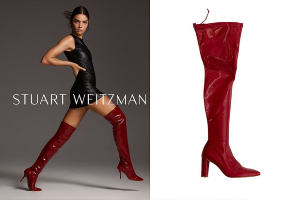 Stuart Weitzman red knee-high boots with a model Kendall Jenner wearing them for the Stuart Weitzman ad campaign on a gray background.