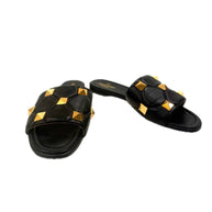 Valentino Garavani Roman Stud Slides in black quilted Nappa leather with gold pyramid studs – angled front view.