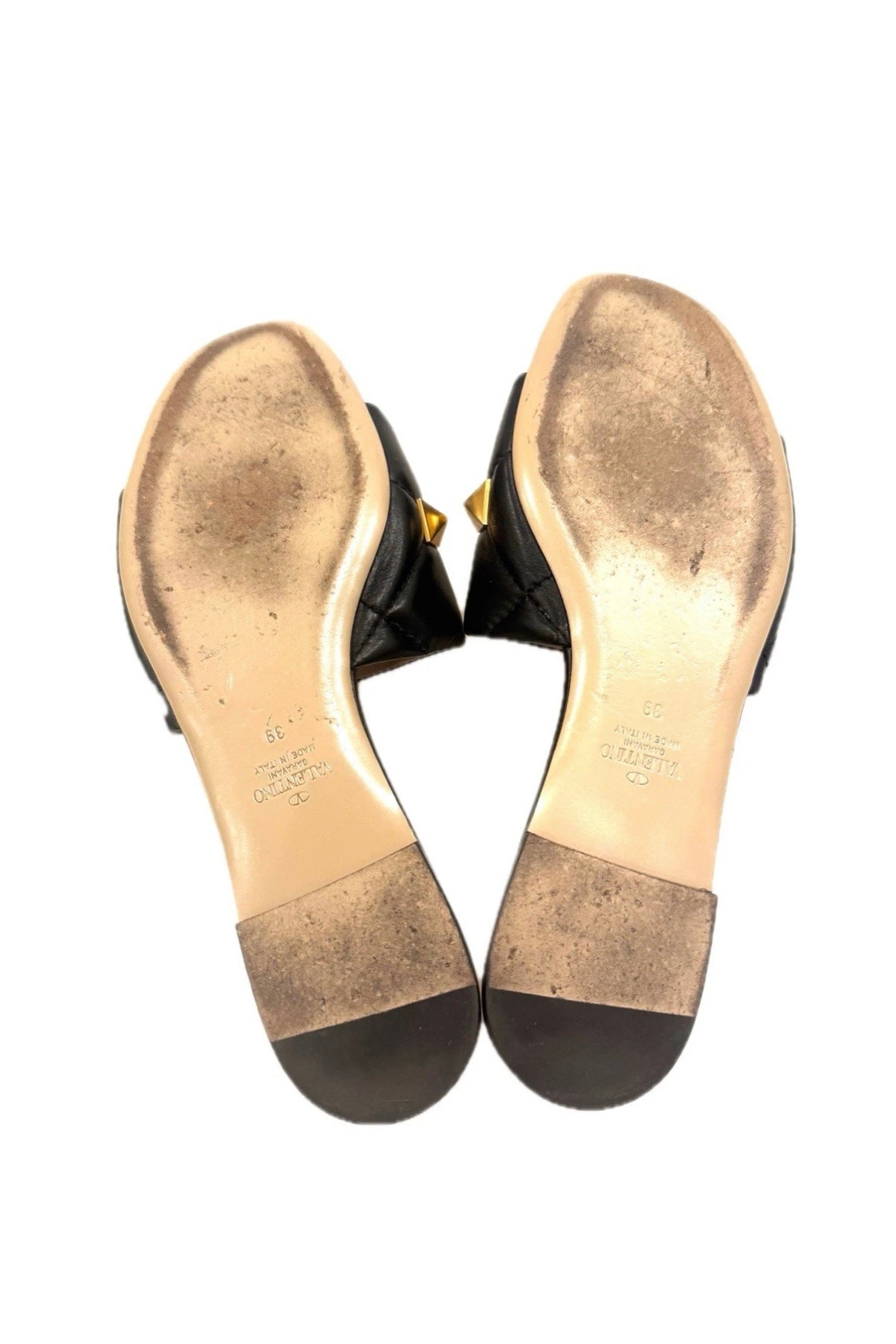 Bottom view of both Valentino Roman Stud Slides showing gold-stamped branding and Italian craftsmanship.
