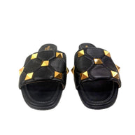 Front view of Valentino Garavani Roman Stud flat slides in black Nappa leather with gold studs.