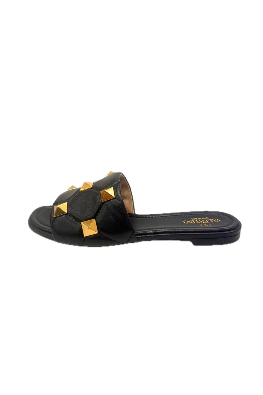 Side view of Valentino Roman Stud Slides in black Nappa leather with oversized gold studs – left shoe.