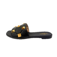 Side view of Valentino Roman Stud Slides in black Nappa leather with oversized gold studs – left shoe.