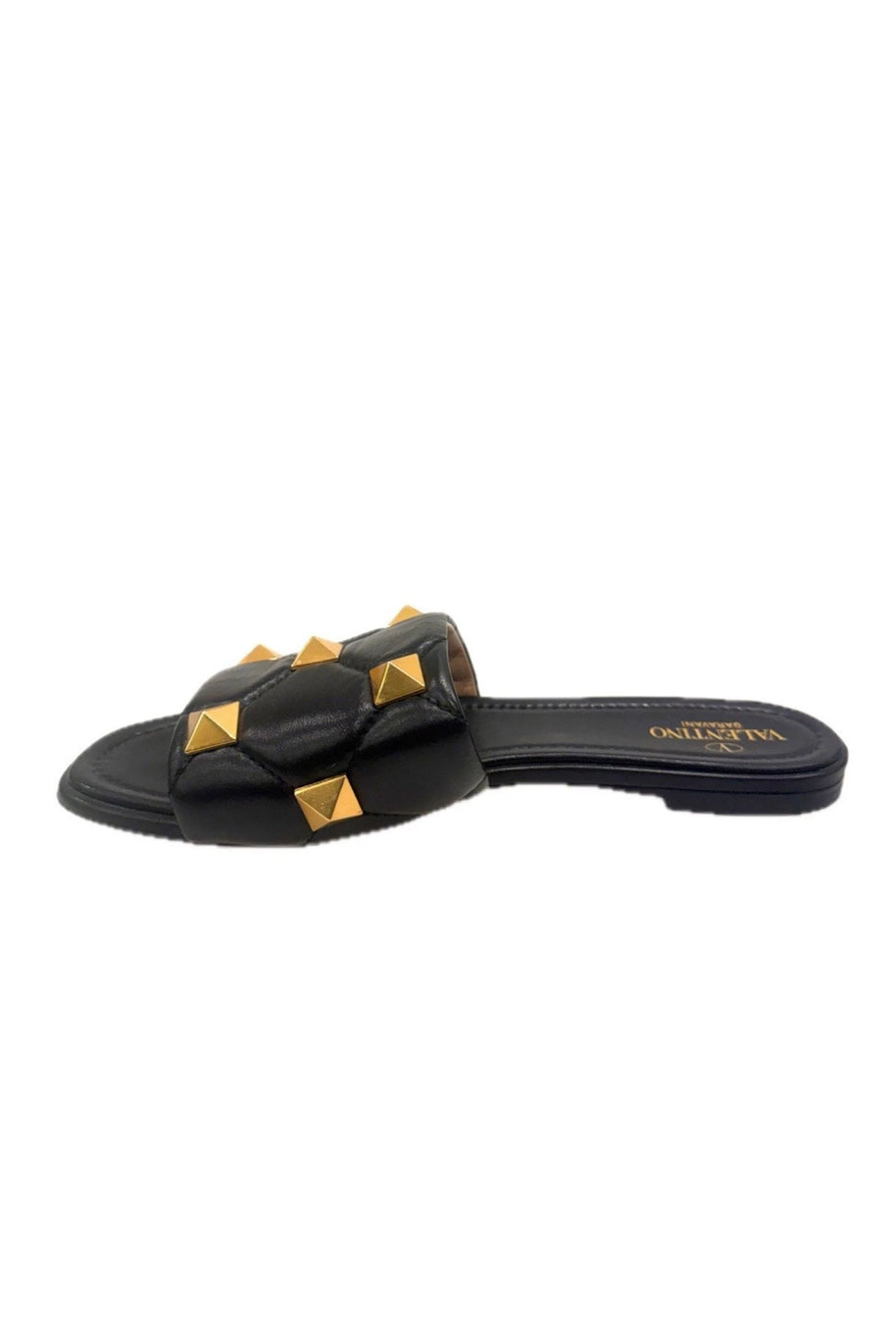 Side angle of Valentino Garavani Roman Stud black leather slides showcasing gold pyramid studs.