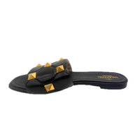 Side angle of Valentino Garavani Roman Stud black leather slides showcasing gold pyramid studs.