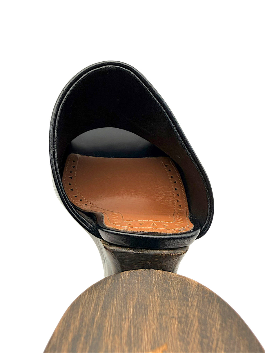 Close-up of Alaïa La Sculpture black leather mule showing the cognac leather insole, decorative perforated stitching and sculptural wooden heel attachment.