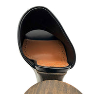 Close-up of Alaïa La Sculpture black leather mule showing the cognac leather insole, decorative perforated stitching and sculptural wooden heel attachment.