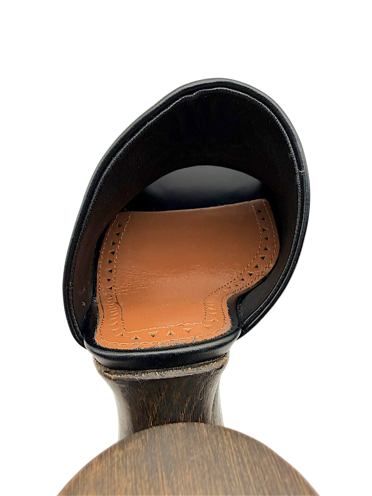 Interior detail of an Alaïa La Sculpture black leather mule showing the cognac leather footbed, decorative perforations and heel construction.