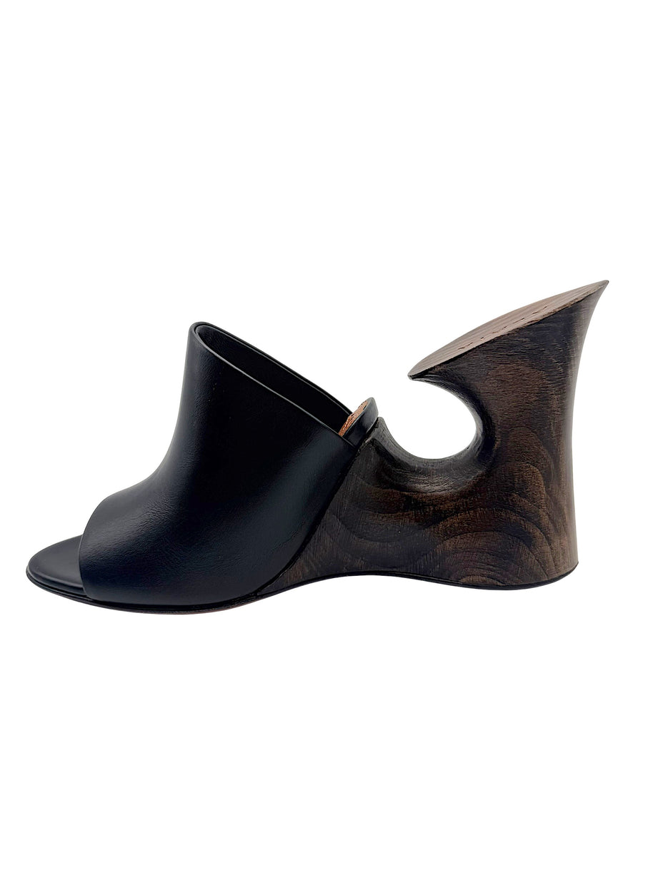 Opposite side profile of an Alaïa La Sculpture open-toe mule with smooth black leather upper and sculptural dark wood heel.