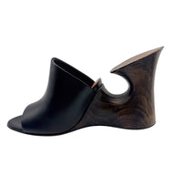 Opposite side profile of an Alaïa La Sculpture open-toe mule with smooth black leather upper and sculptural dark wood heel.