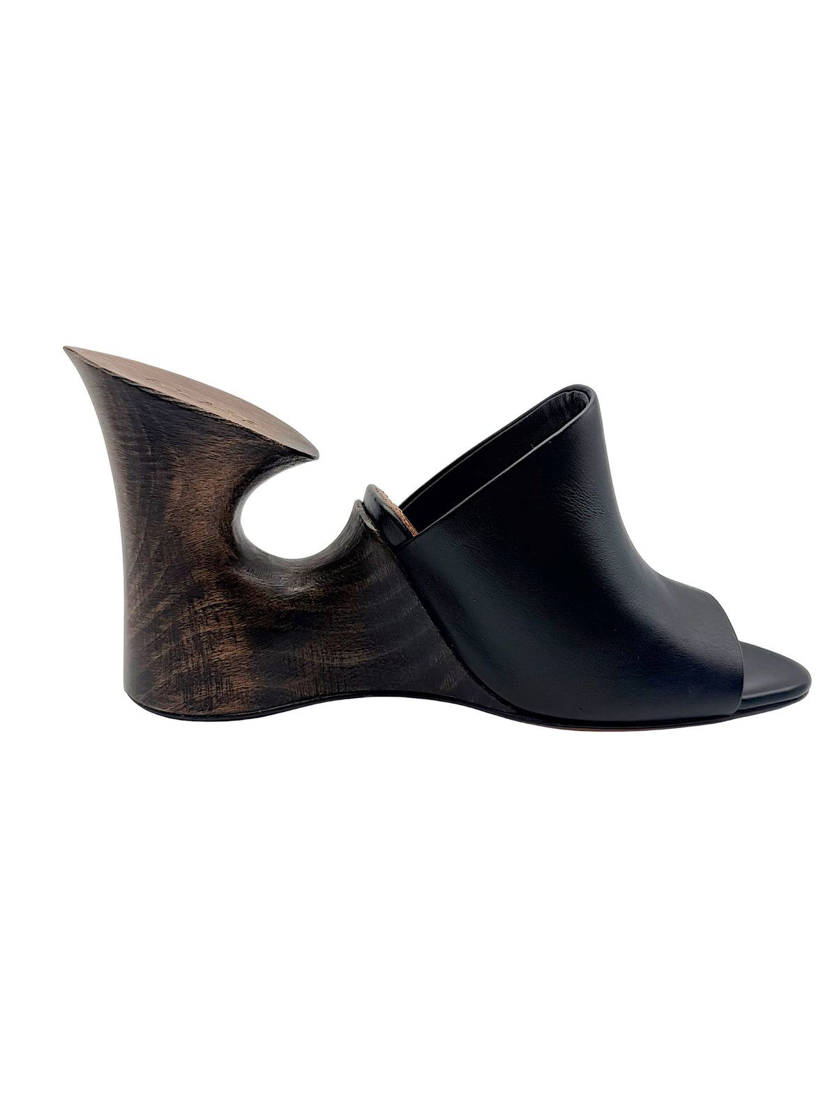 Side profile of Alaïa La Sculpture black leather mule featuring a dark wood-grain sculptural heel and minimalist open-toe design.