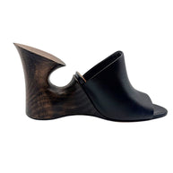 Side profile of Alaïa La Sculpture black leather mule featuring a dark wood-grain sculptural heel and minimalist open-toe design.