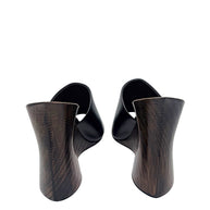 Rear view of Alaïa La Sculpture mules highlighting the curved dark-stained wooden wedge heels and natural wood grain.