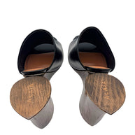 Close-up of Alaïa La Sculpture mules showing Alaïa engraved wooden heel bases, black leather uppers and cognac leather insoles.