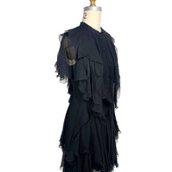 Left three-quarter view of an Alexander McQueen Pre-Fall 2016 black silk chiffon dress with layered ruffles, pleated texture, and sheer flutter sleeves.