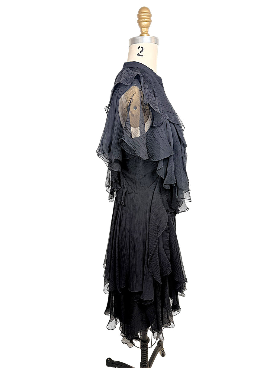 Right three-quarter view of the Alexander McQueen Pre-Fall 2016 black silk chiffon dress showcasing the asymmetrical layered silhouette and fluid drape.