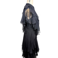 Right three-quarter view of the Alexander McQueen Pre-Fall 2016 black silk chiffon dress showcasing the asymmetrical layered silhouette and fluid drape.