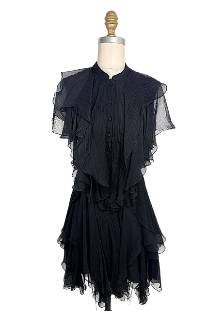 Alexander McQueen Pre-Fall 2016 black silk chiffon dress featuring pleated construction, cascading ruffles, sheer flutter sleeves, and an asymmetrical layered hem, front full view.