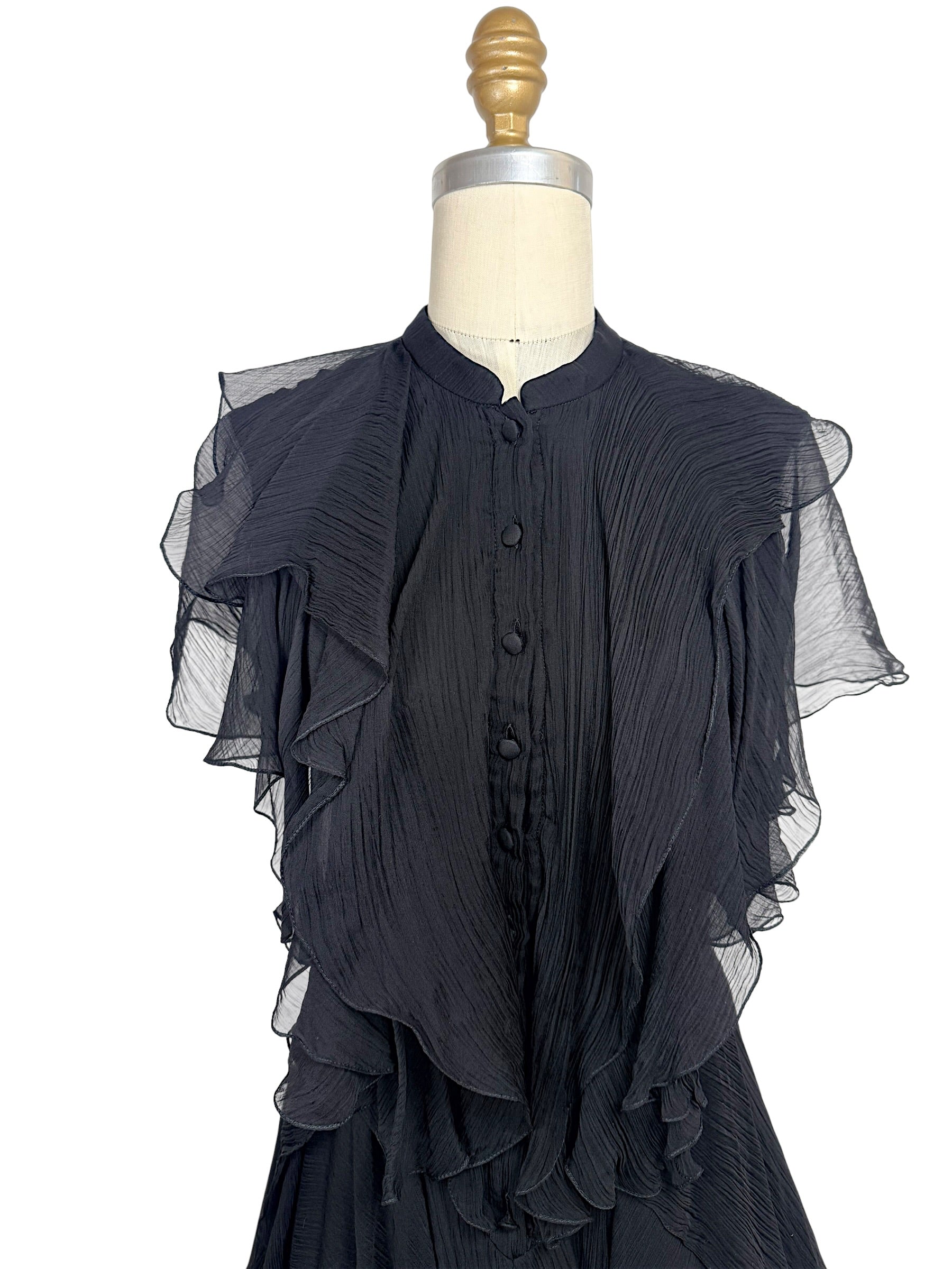 Close-up of the Alexander McQueen Pre-Fall 2016 black silk chiffon dress highlighting the pleated bodice, covered silk buttons, stand collar, and cascading ruffle detailing.