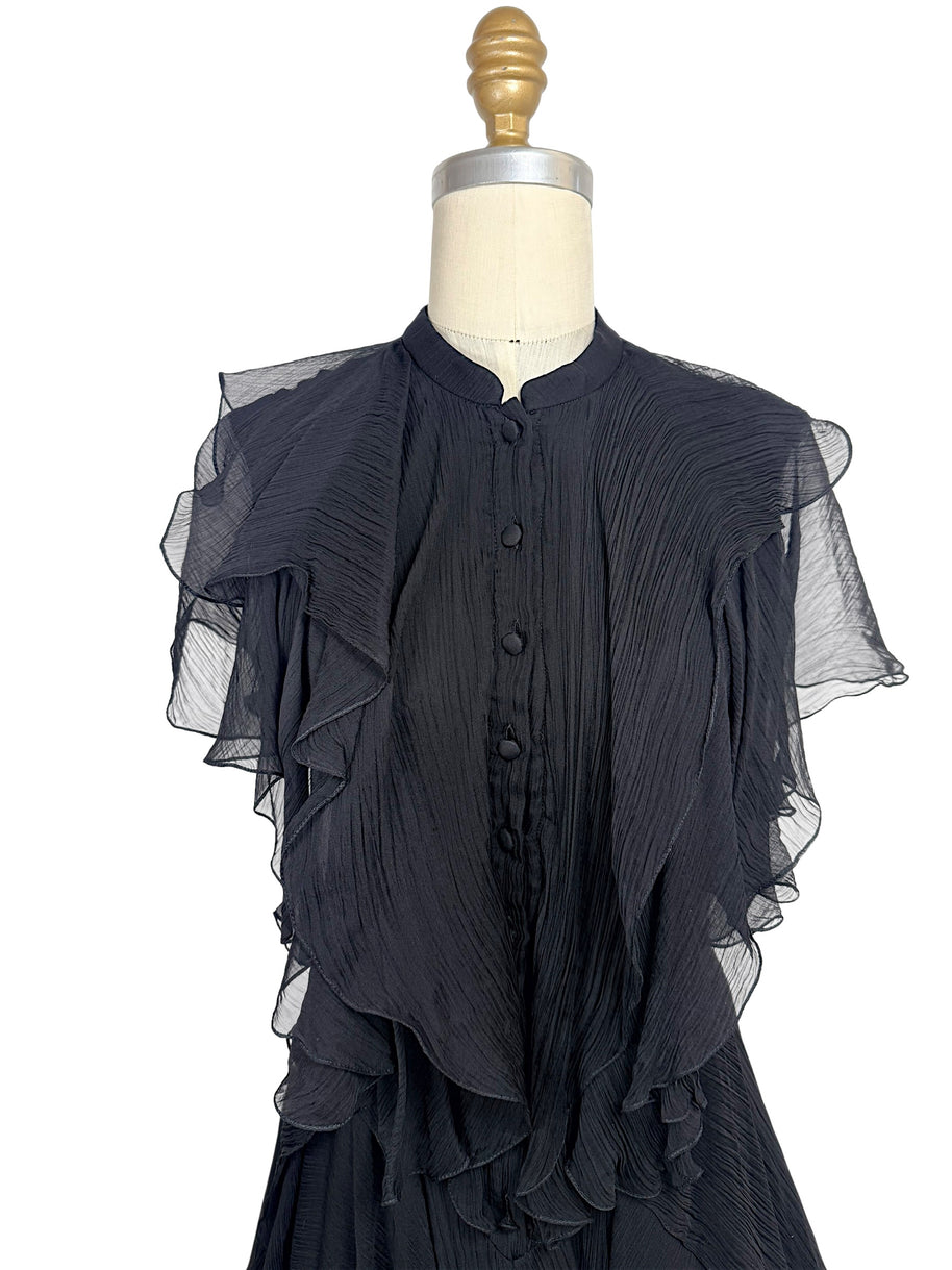 Close-up of the Alexander McQueen Pre-Fall 2016 black silk chiffon dress highlighting the pleated bodice, covered silk buttons, stand collar, and cascading ruffle detailing.