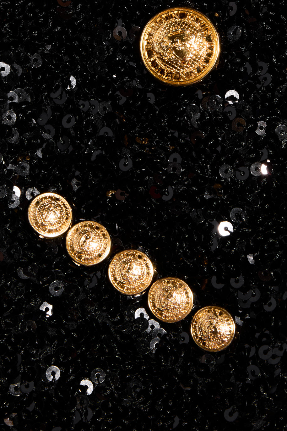 Close-up of embossed gold-tone Balmain buttons and black sequin embellishment