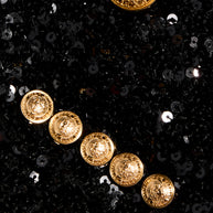 Close-up of embossed gold-tone Balmain buttons and black sequin embellishment