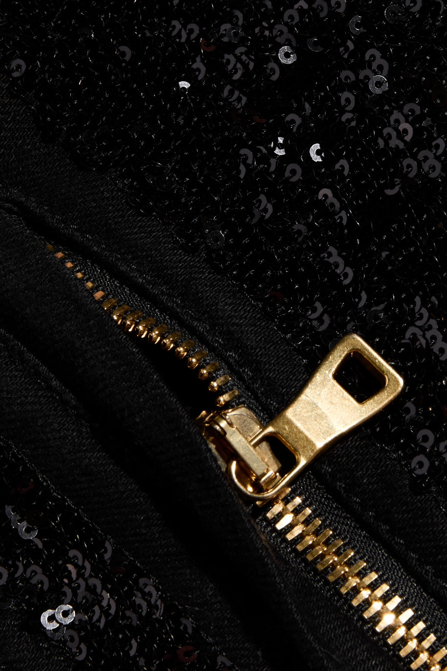 Close-up of gold-tone zipper and black sequin embellishment on Balmain pants