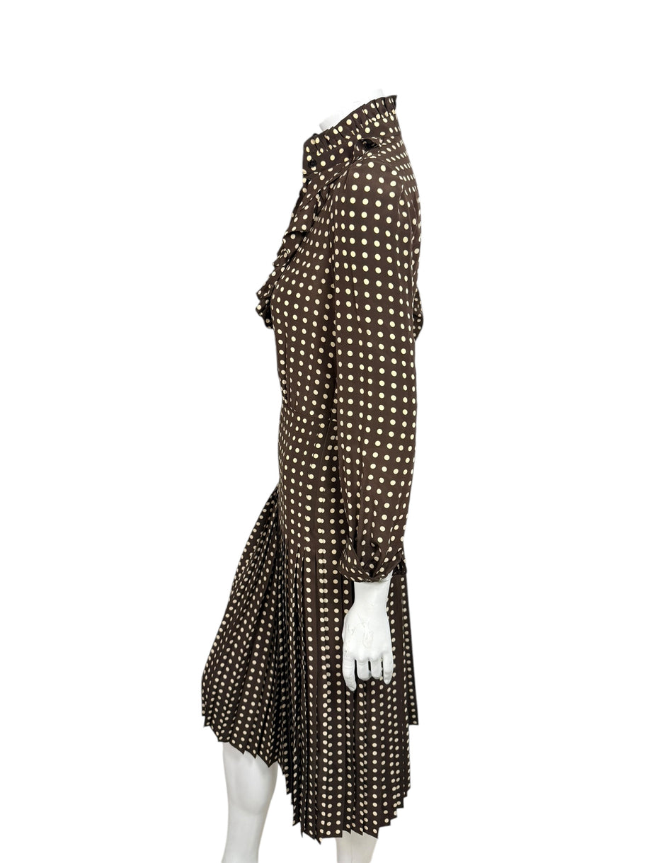 Full-length side profile of Celine Fall Winter 2020 Look 15 brown silk polka dot dress with high ruffled collar and pleated midi hem.