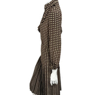 Full-length side profile of Celine Fall Winter 2020 Look 15 brown silk polka dot dress with high ruffled collar and pleated midi hem.