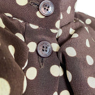 Macro detail of Celine-engraved buttons on chocolate brown and cream polka dot silk fabric from the Fall 2020 runway dress.