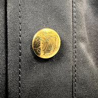 Close-up of gold-tone Celine Paris Triomphe logo button on black cotton skirt, highlighting branded hardware and fabric texture.