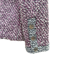 Close-up of Chanel Spring 1996 tweed jacket cuff with signature CC embossed buttons and contrast woven trim