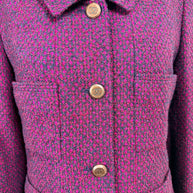 Close-up detail of Chanel 1998 fuchsia and navy tweed fabric with signature engraved CC logo front buttons and patch pockets
