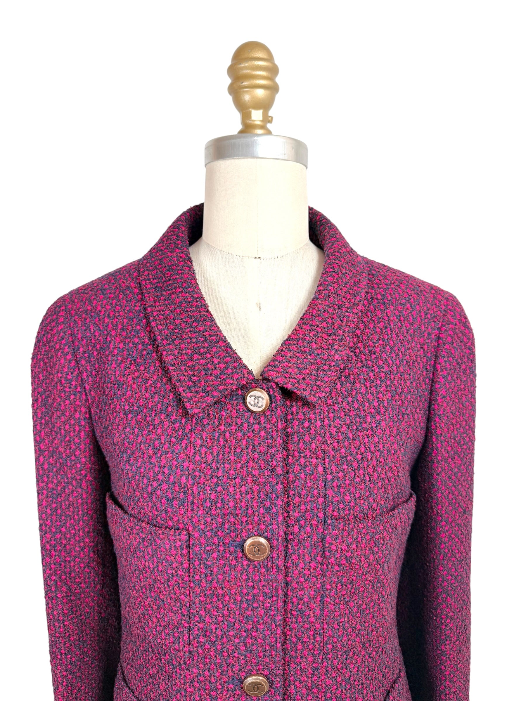 Close-up front detail of Chanel 1998 fuchsia and navy tweed jacket featuring engraved CC logo buttons