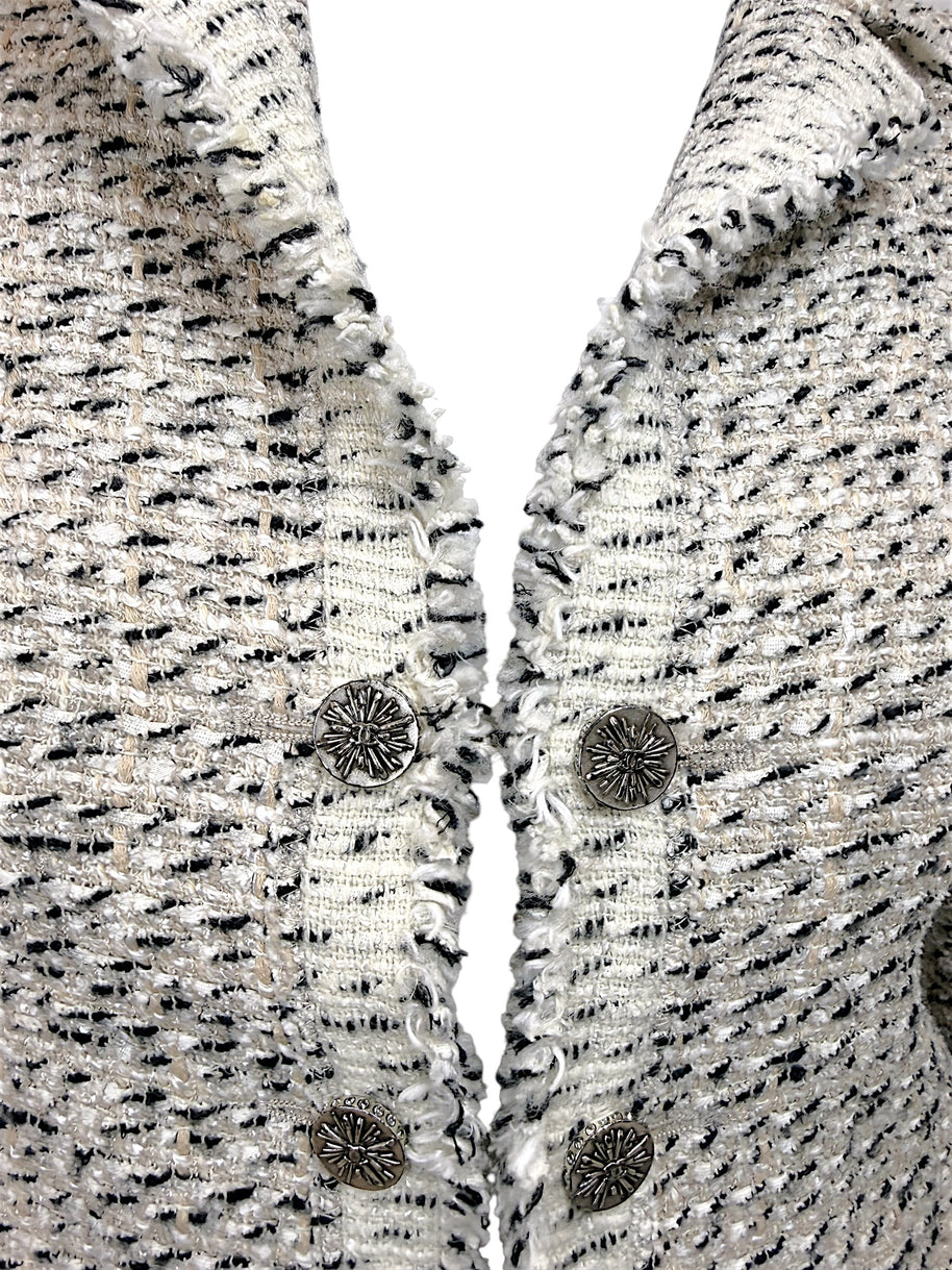 Detailed view of Chanel silver-tone logo buttons and fringe trim on ivory black Lesage tweed jacket from 2004