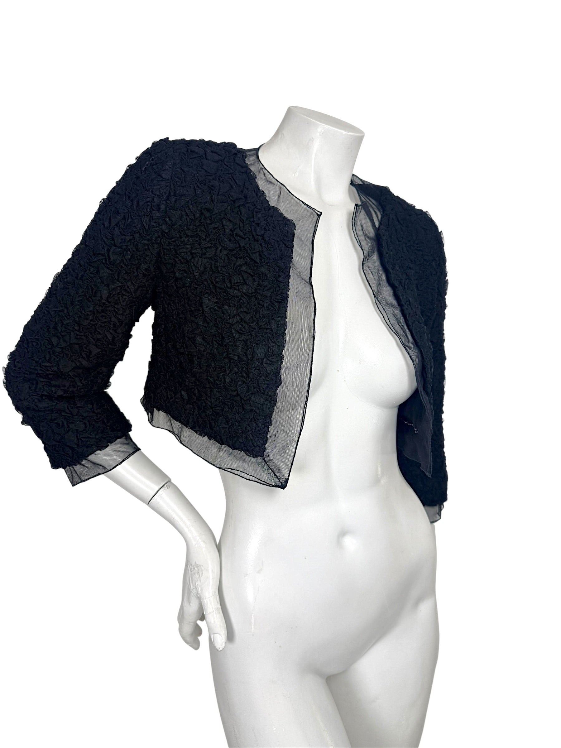 Angled view of Chanel black cropped bolero jacket featuring textured ruched fabric and sheer trim