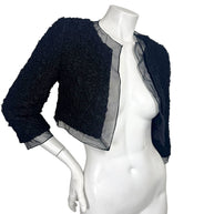 Angled view of Chanel black cropped bolero jacket featuring textured ruched fabric and sheer trim